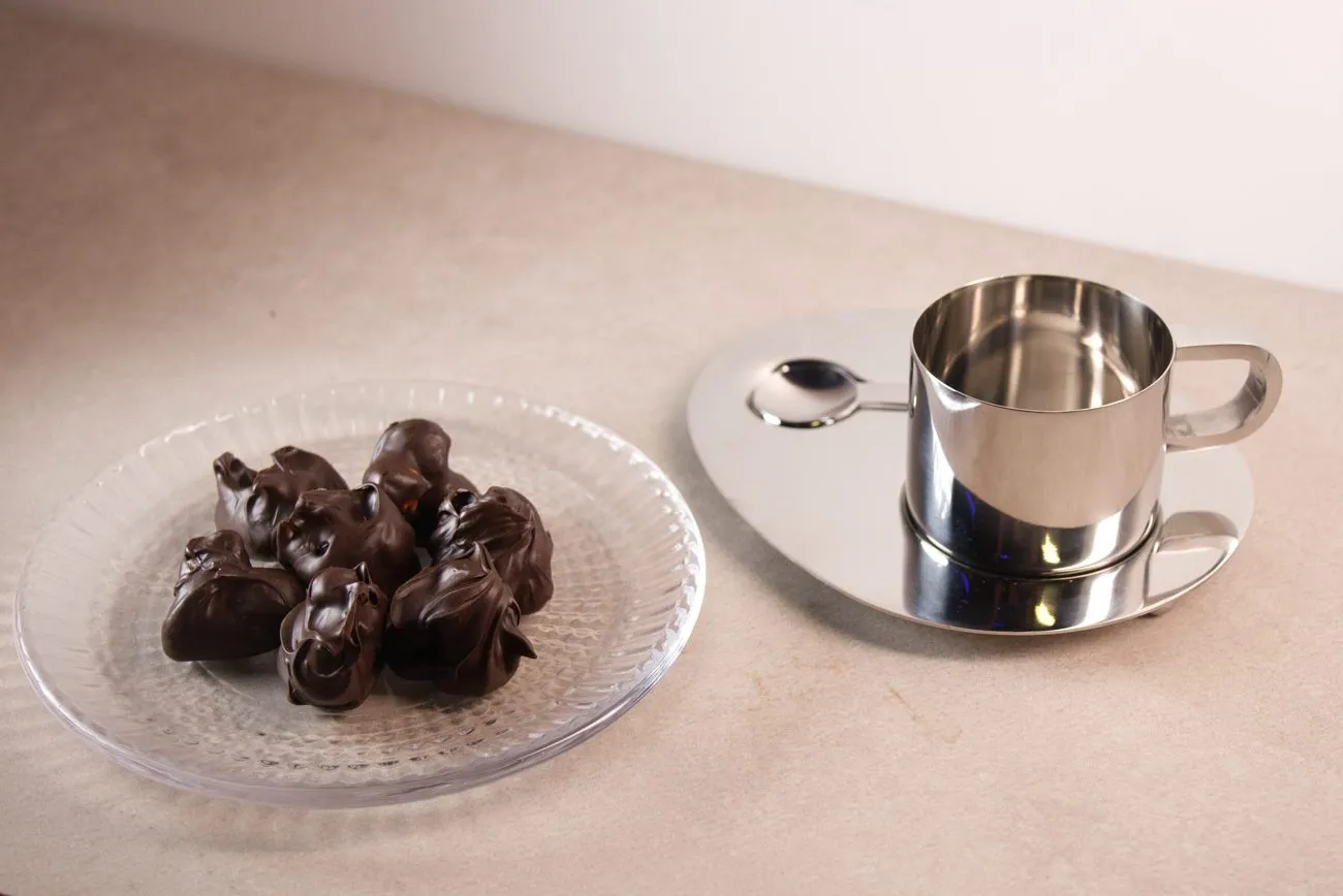 Rocas de chocolate negro en un plato junto a una taza de café